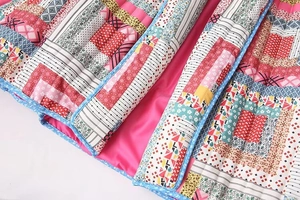 Detail of patchwork quilted jacket with pink lining and blue floral trimmed edges