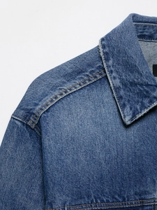 Detailed macro shot of vintage blue denim jacket with distressed edges and stitching