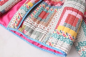Close-up of patchwork quilted jacket with vintage patterns and bright pink inner lining
