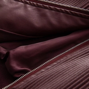 Detail of dark red leather jacket showing metal zipper and knit ribbed cuff texture