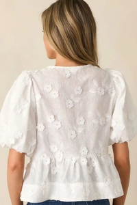 Detailed view of white floral embroidery and puff sleeves on this stylish summer top