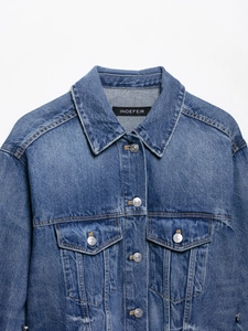 Close-up of a classic blue denim jacket showing collar detail and metal buttons