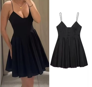 Détail d'une mini robe noire en popeline avec fines bretelles et jupe évasée plissée