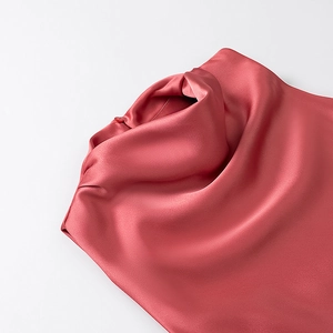Detail of coral red satin dress showing the elegant cowl neck and glossy fabric texture