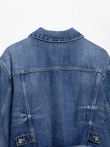 Detail of blue denim jacket back with vintage washing effects and adjustable waist tabs