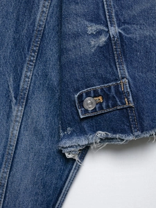 Detail of dark blue denim jacket featuring yellow double stitching and raw hem finish