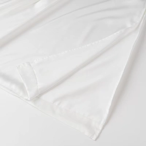 Detail of premium white satin fabric with smooth sheen and precision stitched side slit