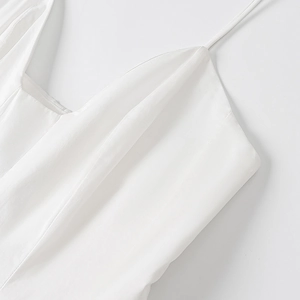 Détail du décolleté de la robe blanche en coton et lin, bretelles et texture du tissu