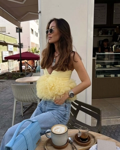Detail of light yellow deep V-neck top with large layered organza floral ruffle at waist