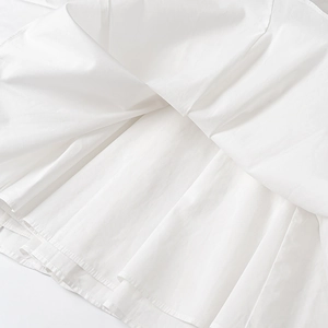 Gros plan sur l'ourlet de robe en popeline avec plis détaillés et épaisseurs de coton