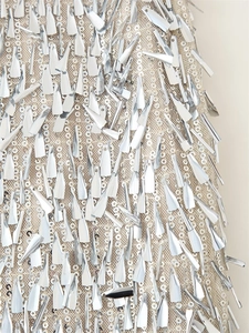 Macro detail of champagne sequins and silver paddle charms on a sequined midi skirt