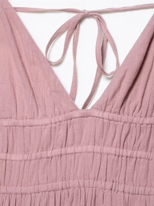 Detail of the deep V-neckline and elastic pleated waist on dusty pink textured fabric