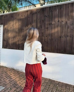 Back view of a chic cream embroidered jacket paired with red striped trousers outdoors