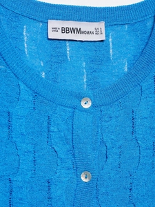 Detail of blue cable knit sweater featuring hollow texture and pearlescent buttons