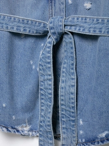 Detailed close-up of light blue distressed denim jacket with tied waist belt and torn design