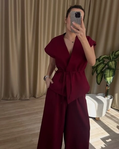 Detail of burgundy sleeveless belted top and high-waist wide-leg pants fashion set