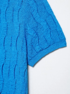 Detail of royal blue short-sleeve knitwear showing intricate hollow knit texture
