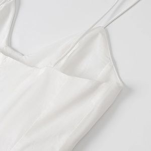 Détail des fines bretelles et des coutures du décolleté en V d'une robe d'été blanche
