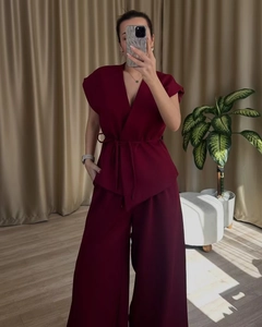 Detail of burgundy wrap top with waist tie and high waist wide leg pants set
