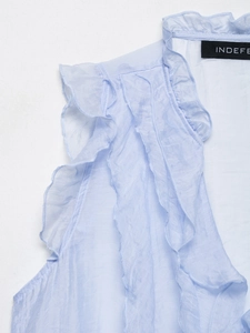Close-up of light blue sleeveless top featuring layered ruffles and brand neck label