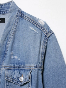 Detailed view of the shoulder stitching and ripped denim texture on the blue jacket