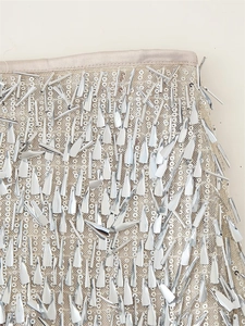 Close-up of champagne mesh fabric with silver sequins and metallic paddle pendants