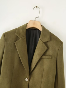 Détail du blazer en suédine vert olive montrant les revers en pointe et le bouton unique