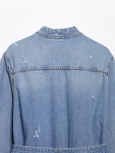 Detail view of light blue denim jacket with distressed ripped back and waist belt