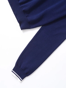 Détail du tissu en maille bleu marine avec poignets côtelés à rayures blanches sur la manche