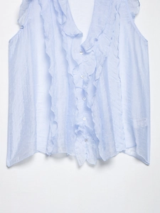 Detail of light blue sleeveless chiffon top featuring ruffled layers and front buttons