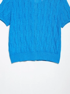 Close-up of royal blue cable-knit short sleeve sweater with intricate texture details