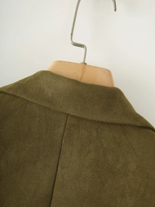 Détail du blazer en daim vert olive montrant la texture du revers et la couture