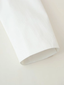 Macro detail of the white blazer cuff showing fine twill fabric and neat stitching