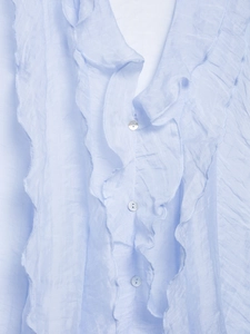 Detail of light blue ruffled sleeveless top showing shell buttons and textured fabric