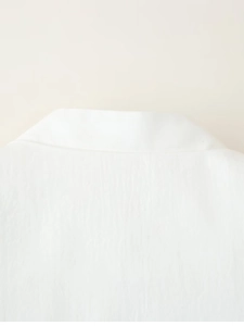 Close-up of white minimalist jacket collar featuring clean embroidery and fabric texture