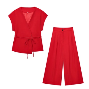 Detail of red two-piece suit showing V-neck wrap top with waist tie and wide-leg trousers
