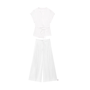 Detail of white wrap top with waist tie and high waist pleated wide leg trousers