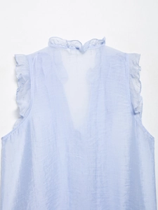 Detail of light blue sleeveless top featuring a ruffled stand collar and pleated silk texture