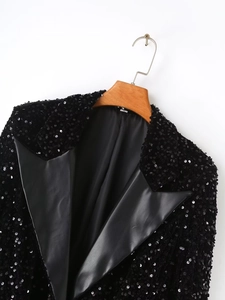 Detail of black sequined blazer with faux leather lapel and size S tag on wooden hanger