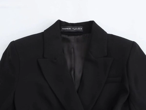 Detail shot of black blazer dress collar with woven fabric texture and brand label