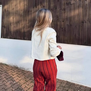 Women's minimalist off-white cropped blazer jacket paired with vertical striped trousers
