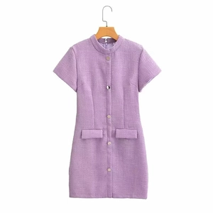 Détail macro du tissu en tweed lilas et des boutons argentés sur la robe à manches courtes