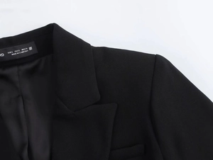 Close-up of black blazer dress collar and shoulder detailing with inner lining texture