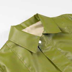 Detailed close-up of grass green faux leather lapel with fine stitching and silver button