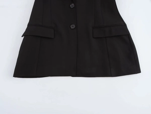 Detail view of black blazer showing two round buttons and symmetrical flap pockets