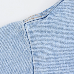 Dettaglio ravvicinato del tessuto denim azzurro con cuciture a contrasto rinforzate