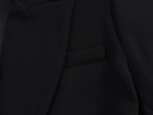 Detail shot of black blazer lapel and pocket with fine woven polyester fabric texture