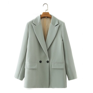 Detail of double-breasted mint green blazer with black buttons and flap pockets