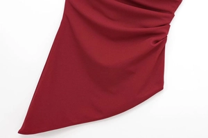 Macro shot of dark red ruched side details and asymmetric hem on women's knit fabric