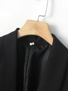 Detail of shawl lapel and size S tag on a black fashion blazer jacket on wooden hanger